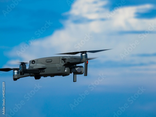 Drone with digital camera, Drone hovering in blue sky with cumulus clouds, Place for Text