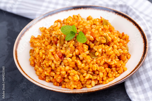 Traditional turkish bulgur pilaf with tomato sause in plate