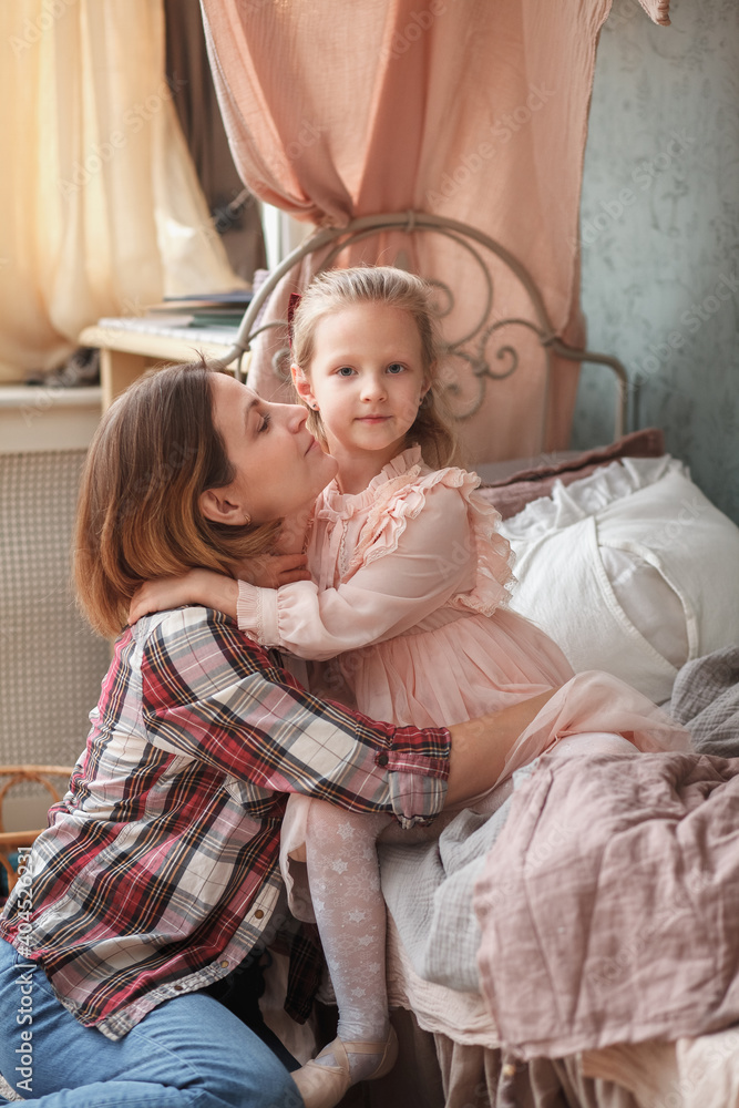 Mother and daughter hug in bedroom close-up