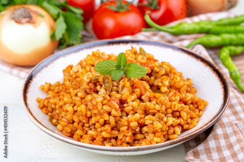 Traditional turkish bulgur pilaf with tomato sause in plate