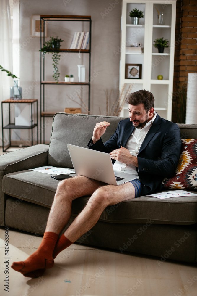 Businessman with no pants working at home. Young man using the laptop having video call..