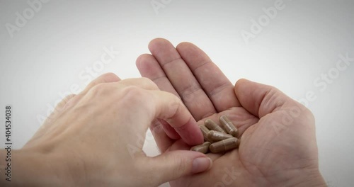 Close up of doctor or pharmacist hand giving brown capsules to the patient in white isolated background. 4k slow motion