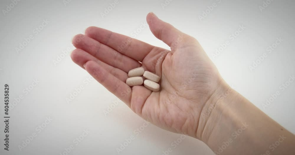 Close up of doctor or pharmacist hand giving brown medicine drugs, pills to the patient in white isolated background. 4k slow motion Close up of doctor or pharmacist hand giving brown medicine drugs, pills to the patient in white isolated background. 4k slow motion