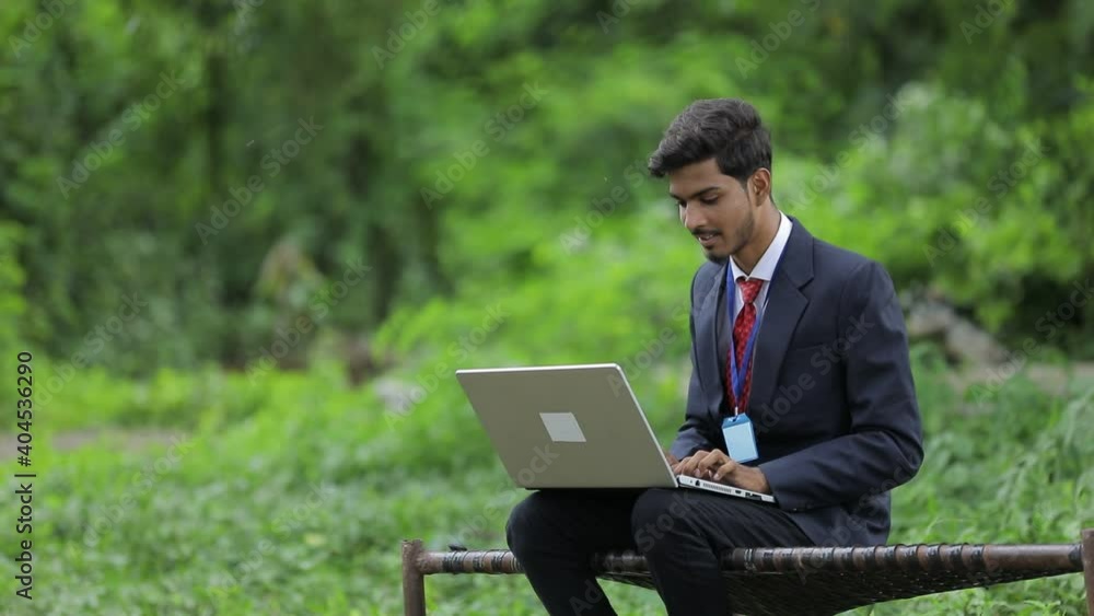 Young indian banker using laptop at field Young indian banker using laptop at field