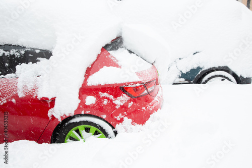 Fragment of a red and blue car and wheels covered with snow. © Natalia