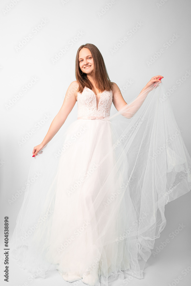 Happy bride. Female elegance. Wedding day. Event shooting. Smiling women in white fluffy organza dress posing on camera in studio isolated on light. Happy bride. Female elegance. Wedding day. Event shooting. Smiling women in white fluffy organza dress posing on camera in studio isolated on light.