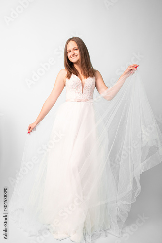 Happy bride. Female elegance. Wedding day. Event shooting. Smiling women in white fluffy organza dress posing on camera in studio isolated on light.