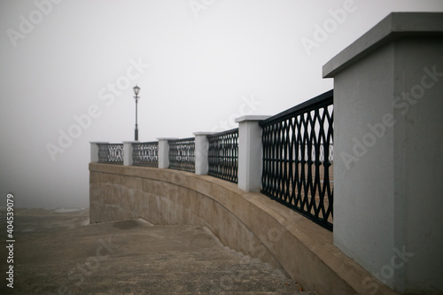 city embankment with lanterns in the early fog