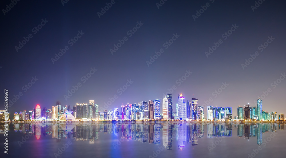 (Selective focus) Stunning panoramic view of the Doha Skyline illuminated at dusk during the Covid-19 pandemic. Doha is the capital and most populous city of the State of Qatar.