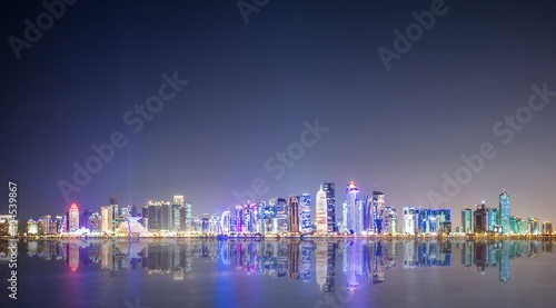 (Selective focus) Stunning panoramic view of the Doha Skyline illuminated at dusk during the Covid-19 pandemic. Doha is the capital and most populous city of the State of Qatar.