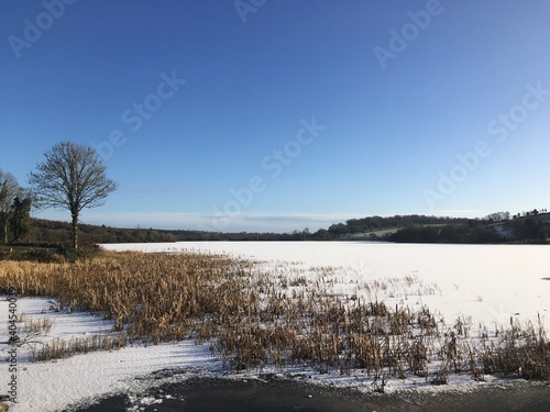 winter landscape, frozen snow covered lake with clear blue sky