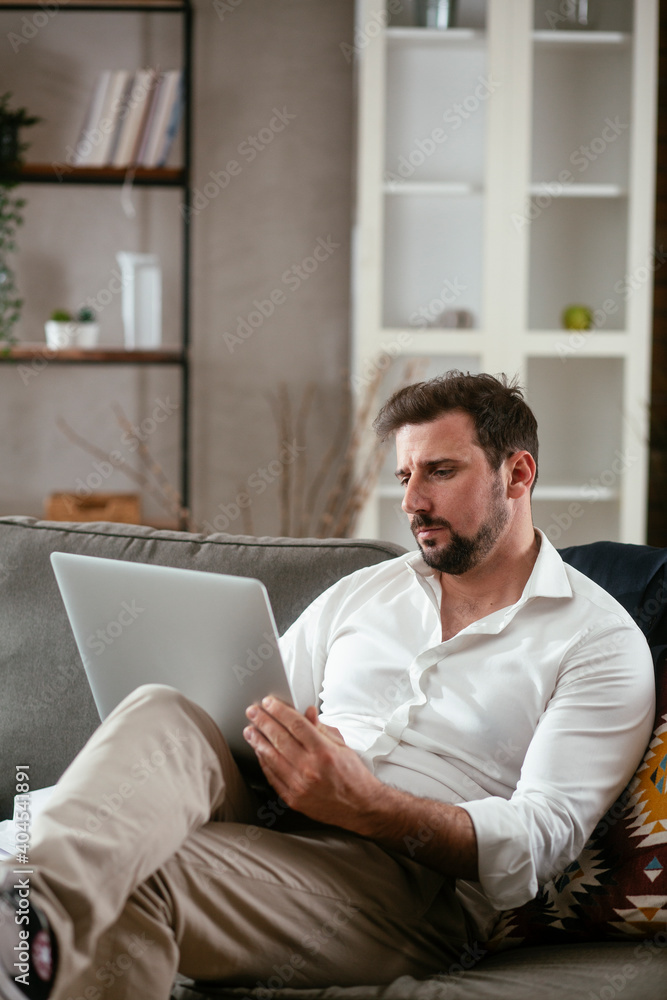 Young businessman working with laptop at office. Businessman sitting on sofa working on laptop computer.. Young businessman working with laptop at office. Businessman sitting on sofa working on laptop computer..