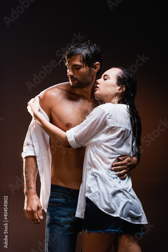 seductive woman taking off wet shirt from sexy man on dark background © LIGHTFIELD STUDIOS