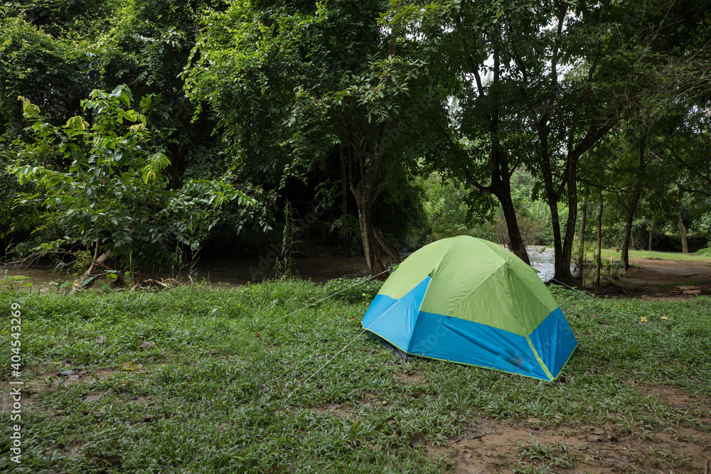 Camping tent on green grass field under cloudy sky