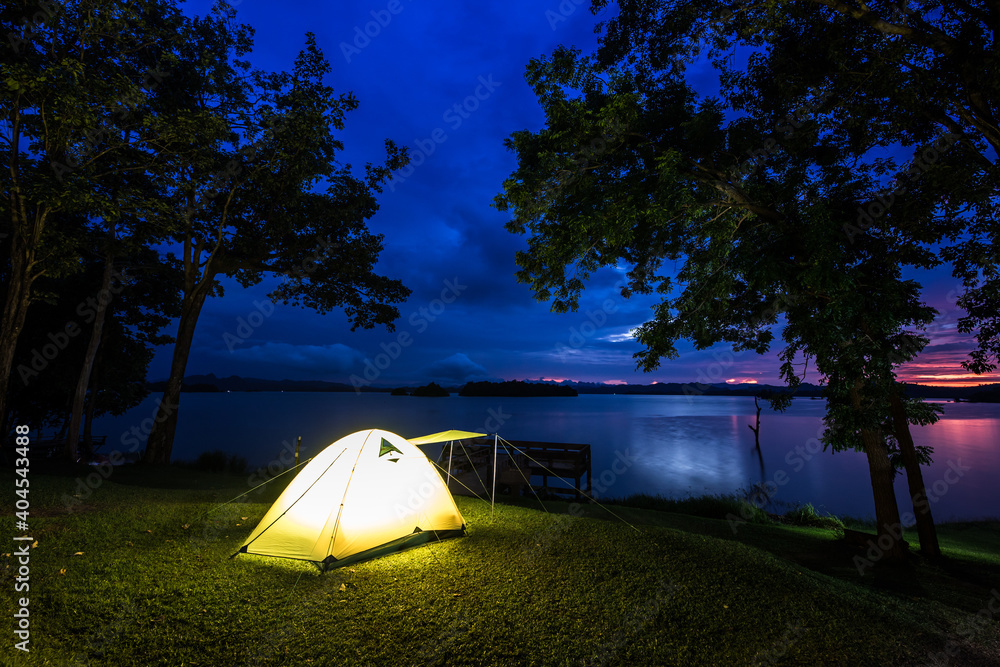 Camping tent on green grass field under cloudy sky at night time