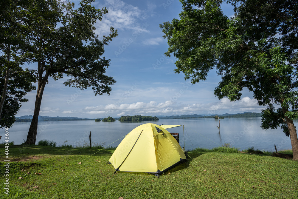 Camping tent on green grass field under cloudy sky