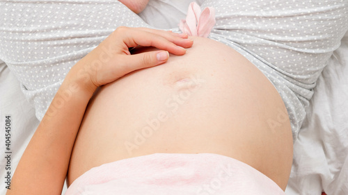 Young pregnant woman expecting child stroking and gently touching her belly. Beautiful pregnancy and anticipation of baby © Кирилл Рыжов