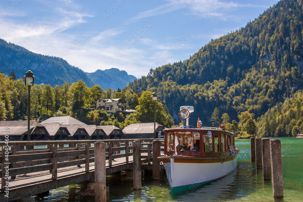 Naklejka premium An electric boat on the Konigsee in Germany stands on a dock, a tourist spot, a vacation spot and beautiful alpine scenery
