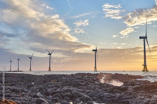Landscape with offshore wind turbine at sunset