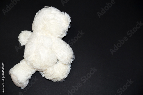 toy white bear face down lies on a black background