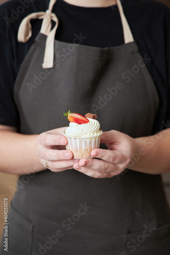 A closeup of a pastry chef holding a cupcake