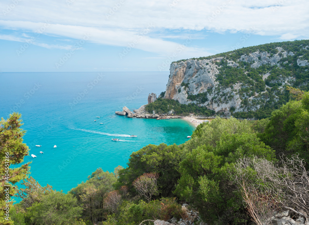 Aerial view of Cala Luna beach near Cala Gonone, Gulf of Orosei, Sardinia island, Italy. White sand beach with lime stone rocks and turquoise blue water. Famous travel touristic destination