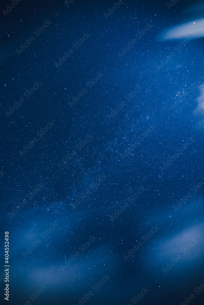Fototapeta premium View of a night blue sky with a stars in the countryside. Milky way under the clouds.