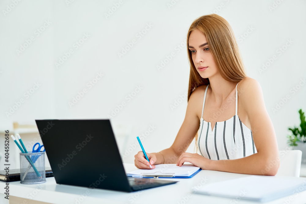 Pretty young businesswoman working on laptop in modern office. Pretty young businesswoman working on laptop in modern office.