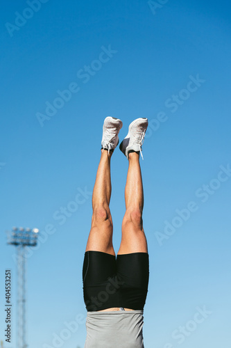 Obraz na plátne Legs of fitness man doing handstand with blue sky