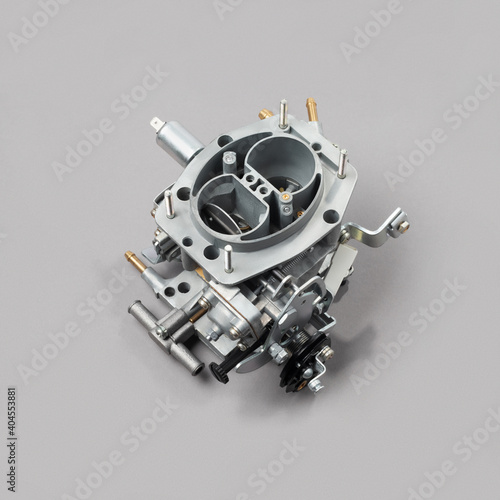 Car carburettor for internal combustion engine for mixing air with a fine spray of liquid fuel on gray background, side view. Automotive parts.