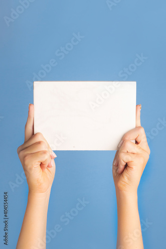 hand holding a blank paper on a colored background