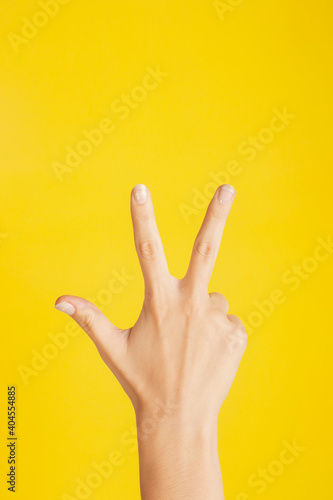 hand making number three on color background