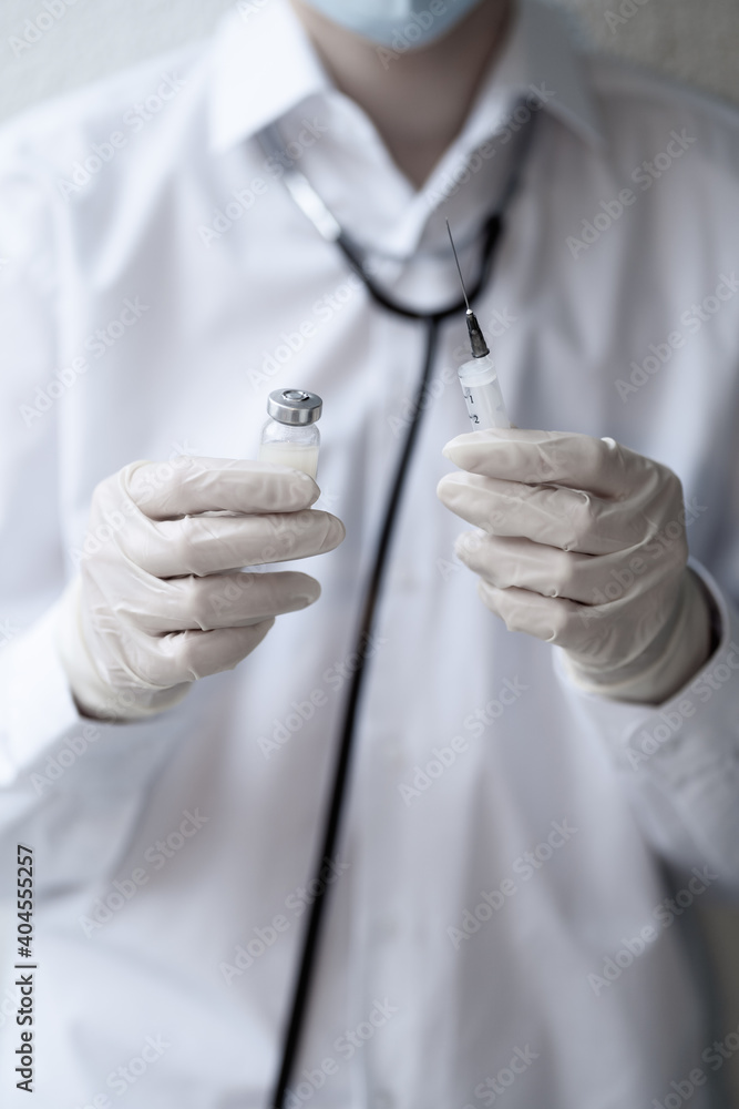 The doctor holds a coronavirus vaccine and a syringe in his hands. Concept. Pandemic. The doctor holds a coronavirus vaccine and a syringe in his hands. Concept. Pandemic.
