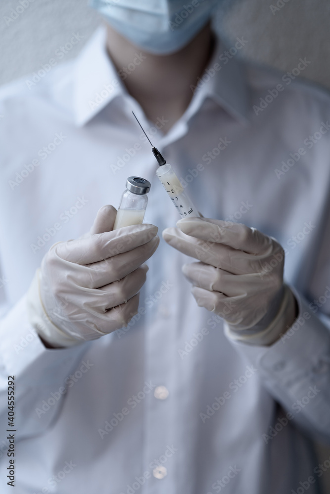 The doctor holds a coronavirus vaccine and a syringe in his hands. Concept. Pandemic. The doctor holds a coronavirus vaccine and a syringe in his hands. Concept. Pandemic.