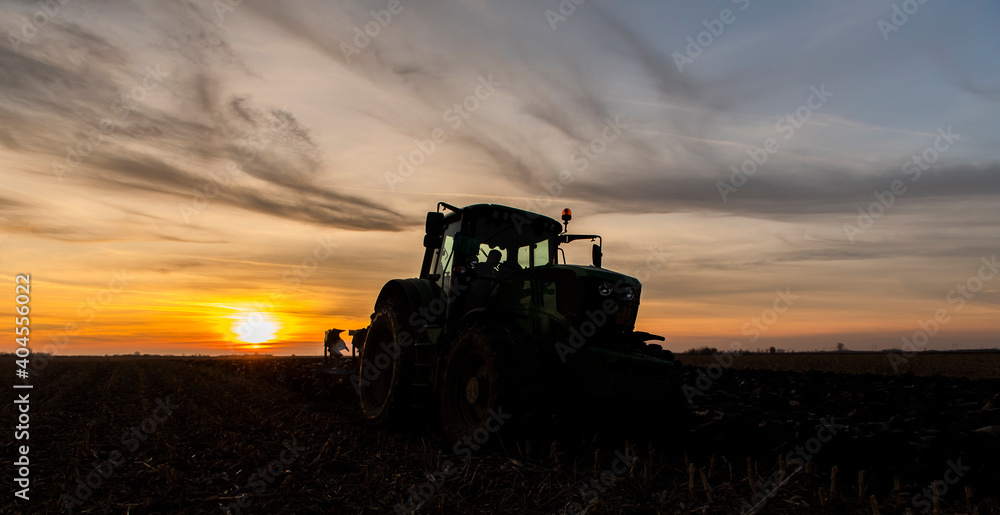 Fototapeta premium Tractor on the field during sunset.