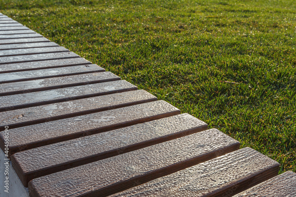 Wooden planks of the bench covered with drops of morning dew. Selective focusing. Wooden planks of the bench covered with drops of morning dew. Selective focusing.