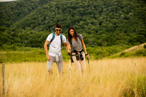 Smiling couple walking with backpacks over green hills