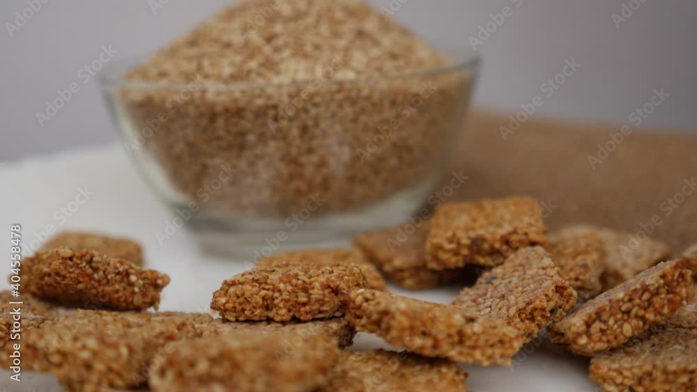 View of bowl filled with sesame seeds and sticks, Sticks of sesame seeds falling on plate View of bowl filled with sesame seeds and sticks, Sticks of sesame seeds falling on plate