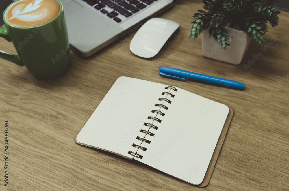 blank notebook lying on a wooden table and a green coffee mug on the computer blank notebook lying on a wooden table and a green coffee mug on the computer
