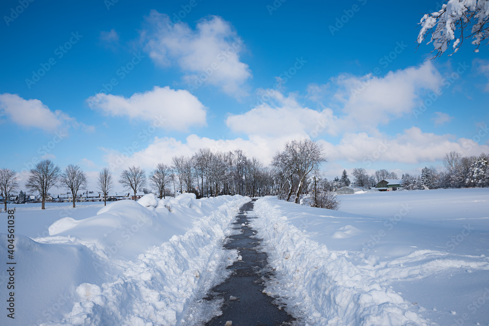 groomed bike and walkway after high amounts of new snow, winter landscape with blue sky groomed bike and walkway after high amounts of new snow, winter landscape with blue sky