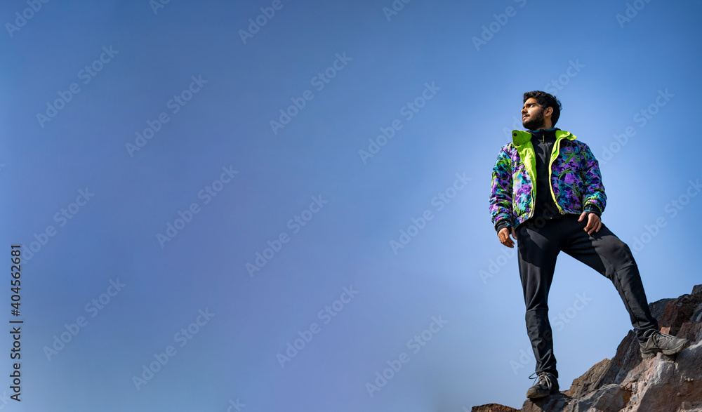 Banner image of a Young Indian boy standing on the top of cliff wearing a snow jacket and track pants. Enjoying and freedom concept. Banner image of a Young Indian boy standing on the top of cliff wearing a snow jacket and track pants. Enjoying and freedom concept.