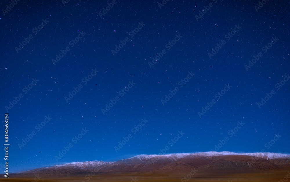 Naklejka premium panoramic view of plain at root of snow-covered mountains on blue sky background