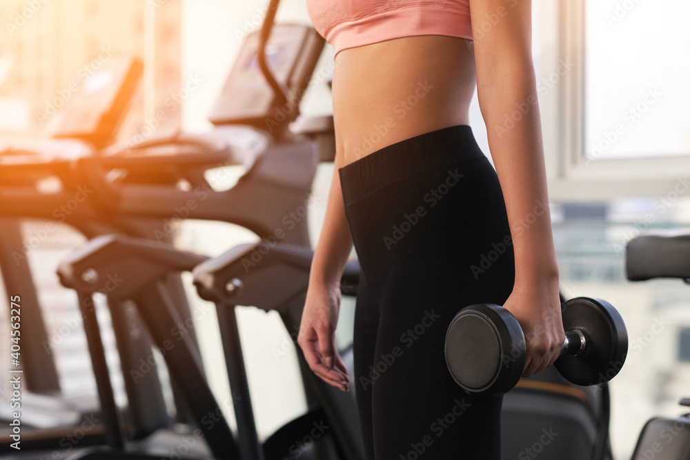 Workout in gym by a beautiful Asian woman , woman is using dumbbell . Sport woman warm up before workout .
