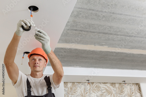 The electrician is installing LED spotlights on the ceiling.