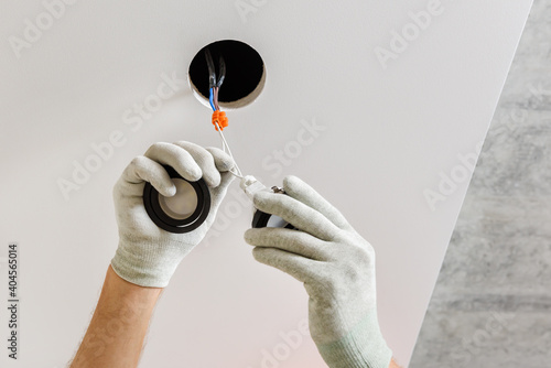 An electrician is installing LED spotlights on the ceiling.