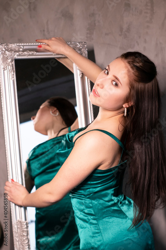 sexy attractive brunette woman in elegant green aquamarine dress in front of a mirror. beautiful sensual girl © OliaVesna