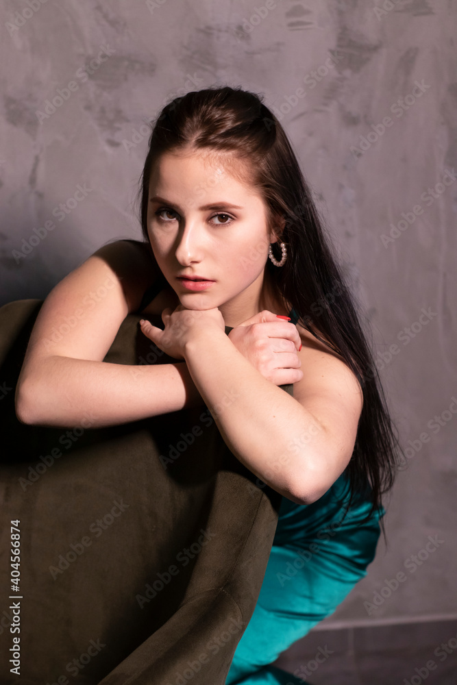 sexy attractive brunette woman in elegant green aquamarine dress in a loft cafe. beautiful sensual girl
