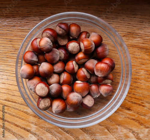 Hazelnut in glass bowl on wooden background. Organic hazelnut harvest. 