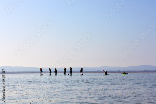 People row on SUP and kayaks at lake in winter season