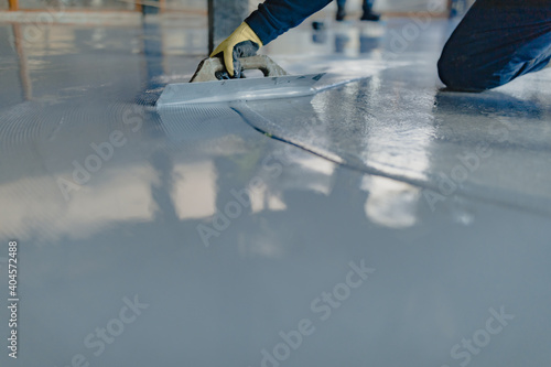The worker applies gray epoxy resin to the new floor